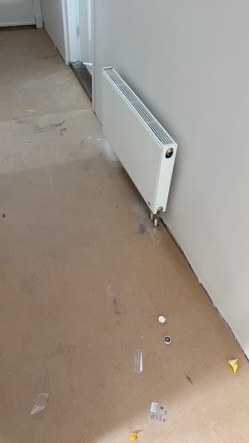 Nieuwe radiator gemonteerd langs wand in gang